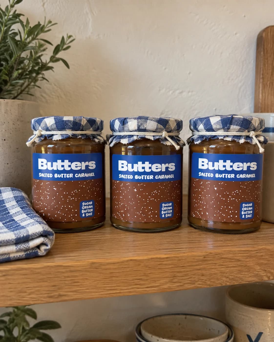 Three Butters Caramel scatter jars lined up on a wooden kitchen shelf