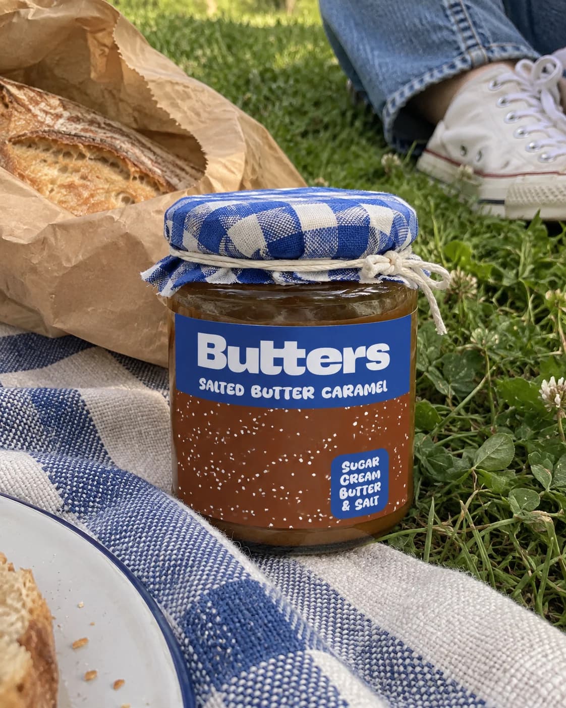 A Butters Caramel scatter jar beside bread on a picnic blanket